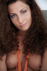 Naked babe plays with favorite orange beads in bed.