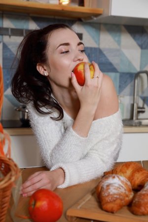 Naked chick eats fresh buns in the kitchen photo 1