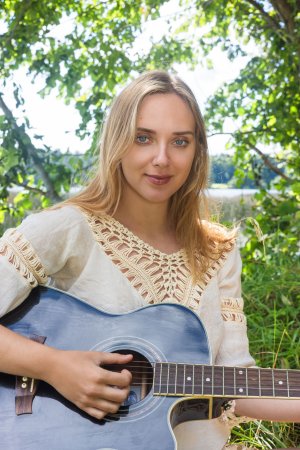 Oxana Chic plays guitar in the meadow photo 1
